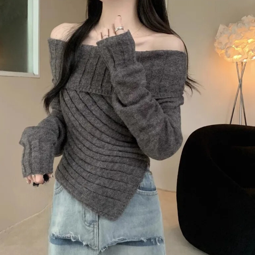 Grijze off-shoulder trui met geribbelde textuur, gedragen door model. Trendy damesmode, casual stijl, herfstkleding, comfortabele pasvorm.