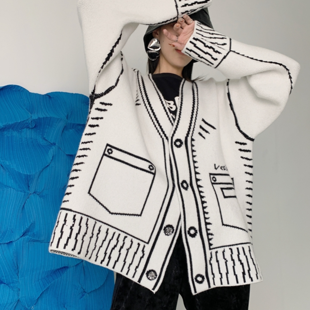 Witte oversized cardigan met zwarte strepen en zakken, gedragen door model. Trendy damesmode, comfortabele gebreide stof, casual stijl.