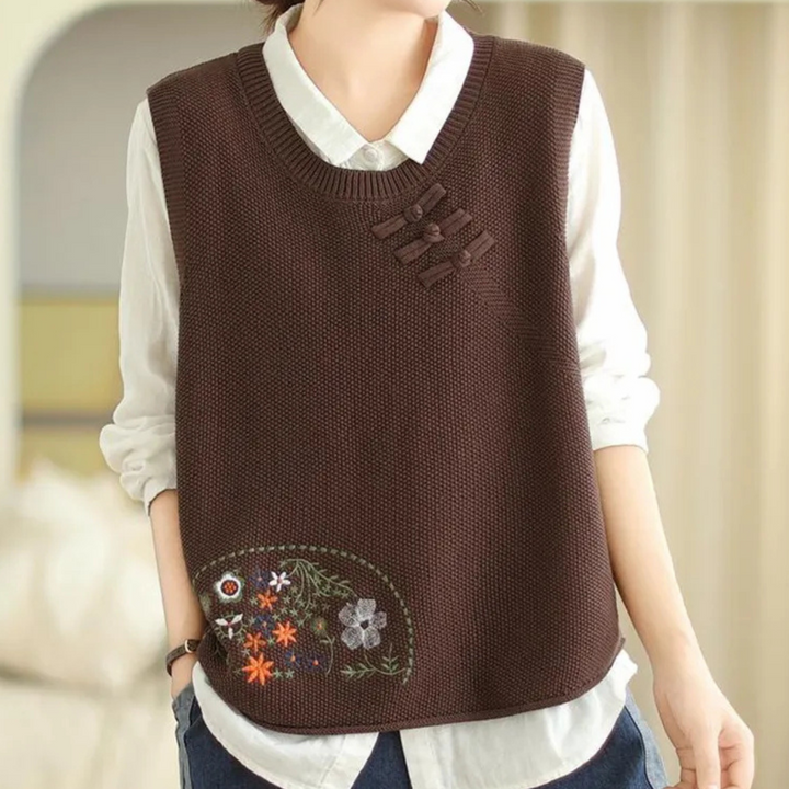 Bruine gebreide spencer met bloemenborduursel, gedragen over een witte blouse. Trendy damesmode, herfstkleding, casual stijl.