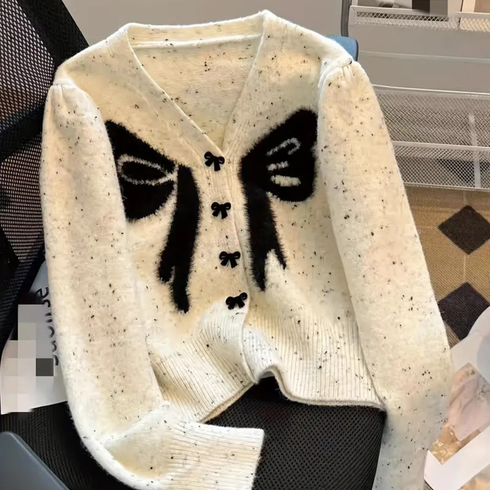 Witte gebreide cardigan met zwarte abstracte gezichten, V-hals en knoopsluiting. Modieuze dameskleding, trendy design, comfortabele pasvorm.