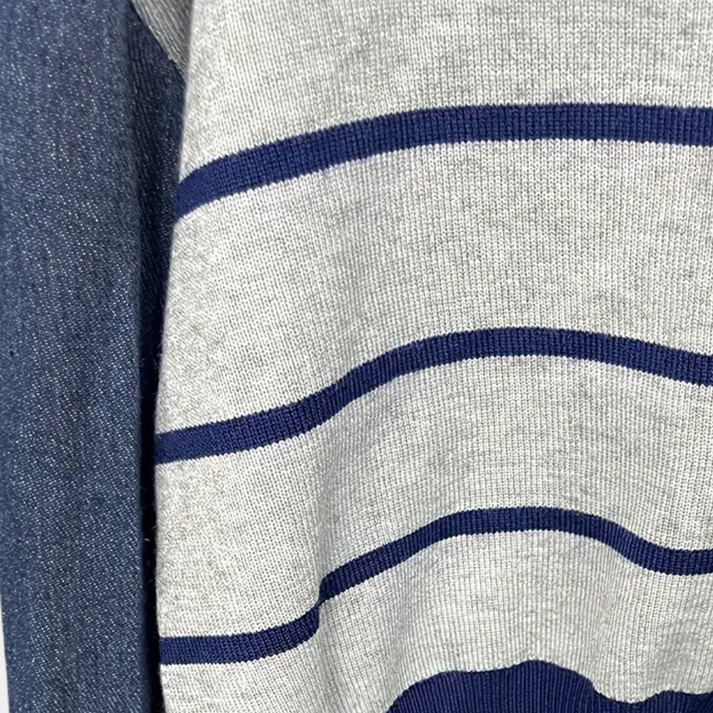 Grijs-wit gestreepte trui met blauwe strepen, close-up detail. Modieuze herenkleding, comfortabele gebreide stof, casual stijl.
