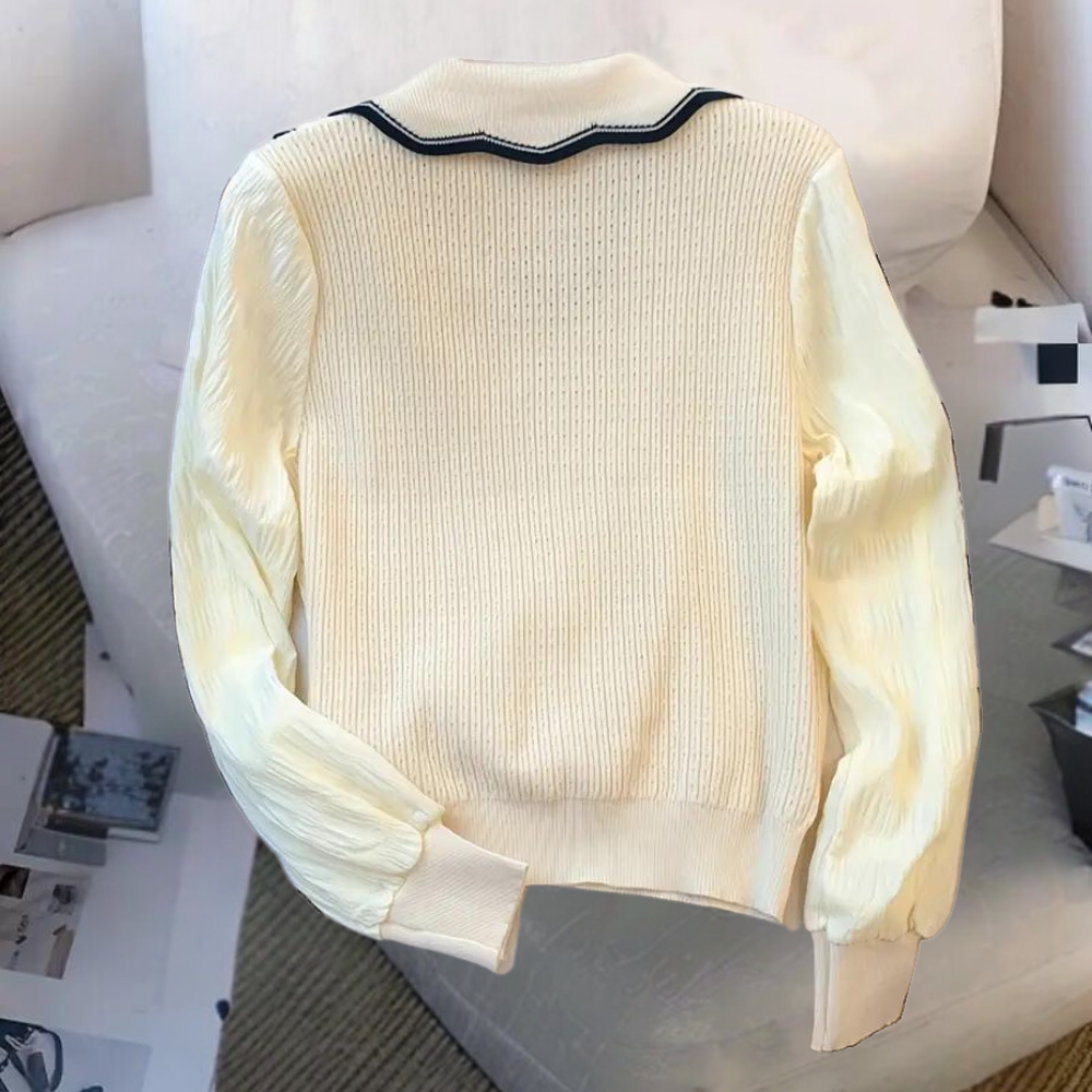 Crèmekleurige gebreide trui met geribbelde textuur en zwarte kraagdetail, perfect voor herfstmode. Stijlvolle dameskleding, comfortabele pasvorm.
