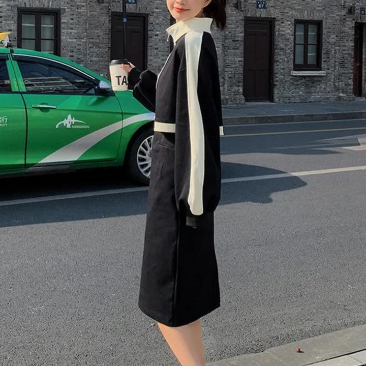 Vrouw in zwarte jurk met witte strepen, wandelend op straat naast groene taxi. Stijlvolle mode, stedelijke achtergrond, casual outfit.