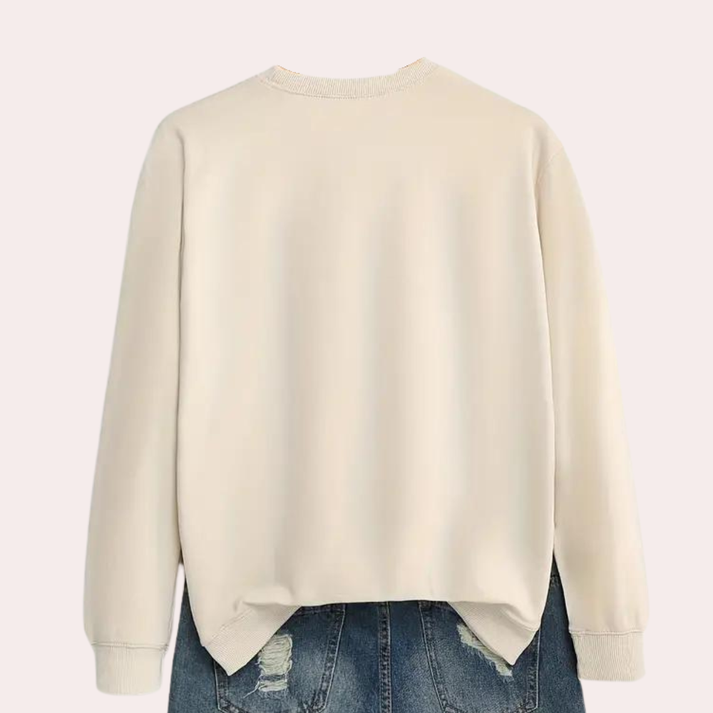 Crèmekleurige sweater met ronde hals en lange mouwen, gedragen boven een blauwe spijkerbroek. Comfortabele casual mode voor dames.