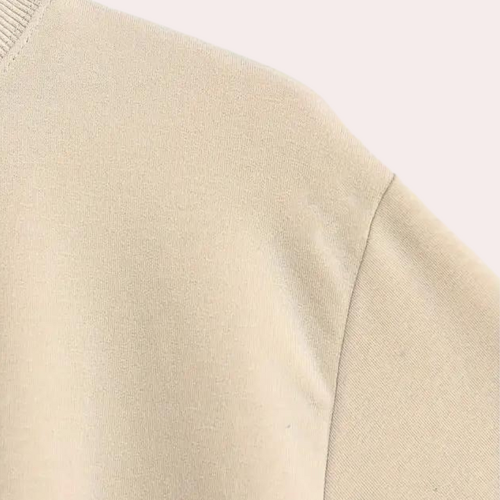 Beige katoenen trui, close-up van de stof en naad, minimalistisch ontwerp, comfortabele casual kleding, modetrend, uniseks, duurzaam materiaal.