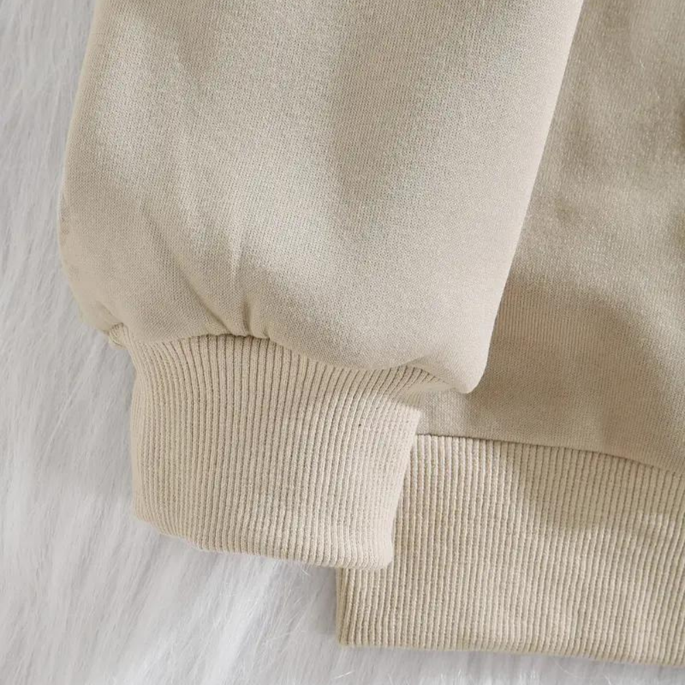 Beige sweater met geribbelde manchetten en zoom, close-up. Comfortabele, casual kleding, ideaal voor herfst- en wintermode. Zachte stof.
