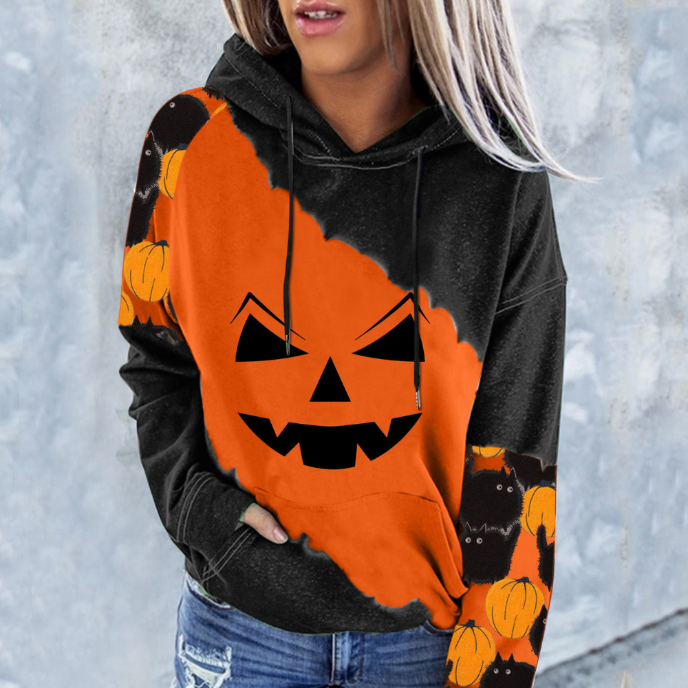 Vrouw draagt Halloween hoodie met oranje pompoenprint en griezelig gezicht, perfect voor herfstmode en feestelijke kleding.