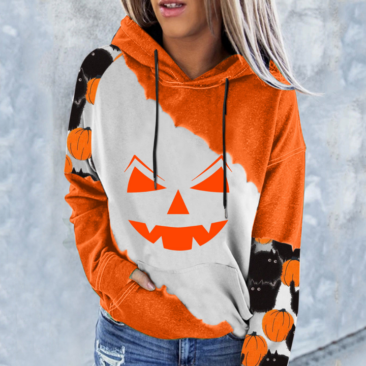 Vrouw draagt oranje-witte Halloween hoodie met pompoenprint en spookmotief. Trendy herfstmode, casual streetwear, comfortabele kledingstijl.