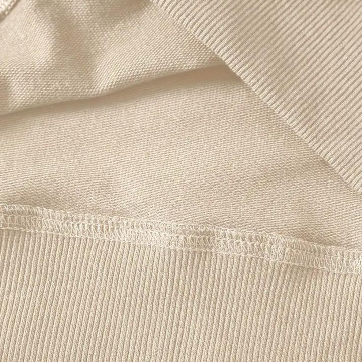 Beige katoenen stof close-up, ribbelstructuur, naad details. Perfect voor modeontwerp, textielproductie, hoogwaardige kledingmaterialen.