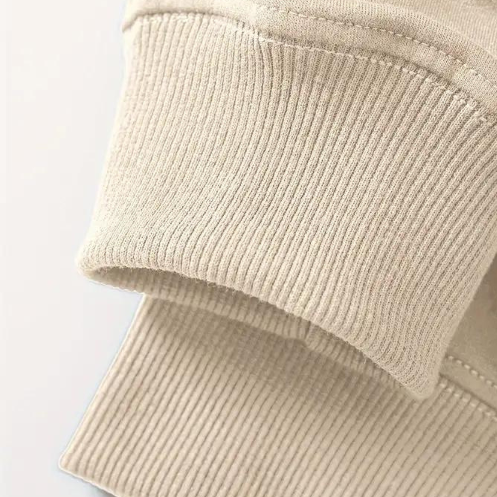 Beige gebreide trui mouw detail, close-up. Hoogwaardige katoenen stof, geribbelde afwerking. Modieuze dameskleding, comfortabele pasvorm.