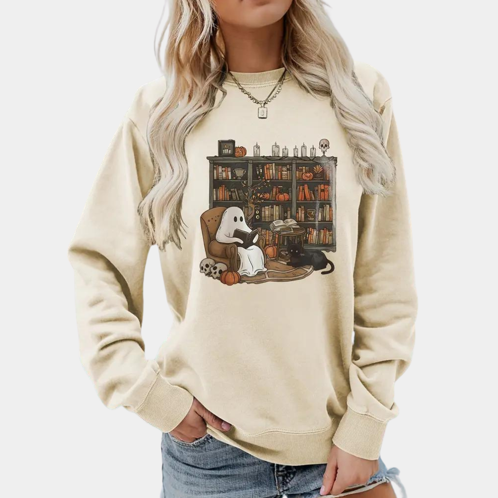 Vrouw draagt beige trui met Halloween-print van spook in bibliotheek. Trendy herfstmode, casual outfit, comfortabele kledingstijl.