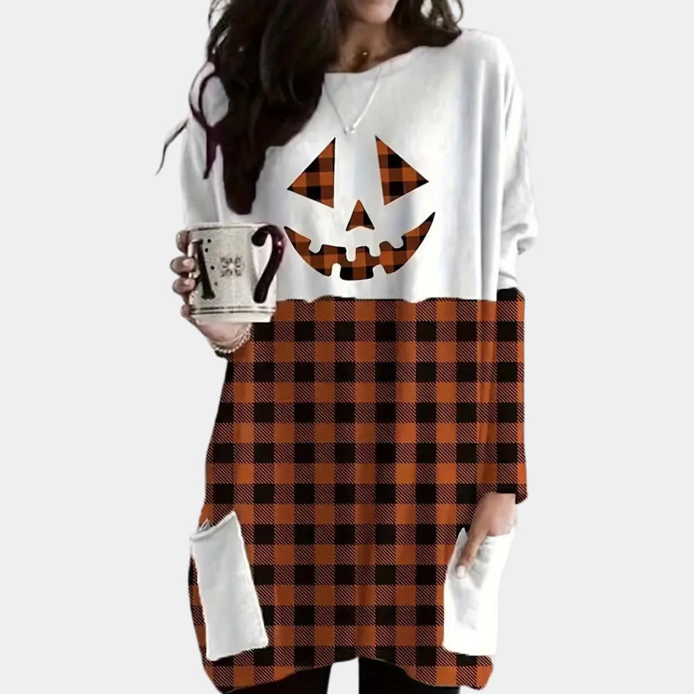 Vrouw draagt Halloween-trui met pompoengezicht en zwart-oranje ruitpatroon, houdt mok vast. Herfstmode, casual kleding, trendy outfit.