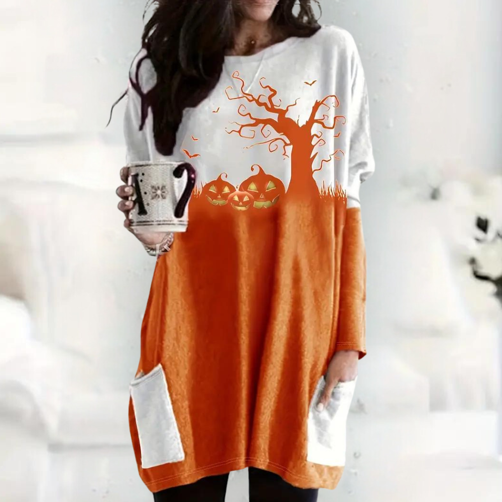 Vrouw in oranje-witte Halloween-trui met pompoenen en boomprint, houdt mok vast. Comfortabele herfstmode, casual stijl, lange mouwen.
