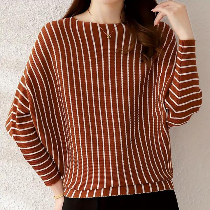 Vrouw draagt bruin-wit gestreepte trui, lange mouwen, ronde hals. Modieuze dameskleding, herfst-winter stijl, casual chic outfit.