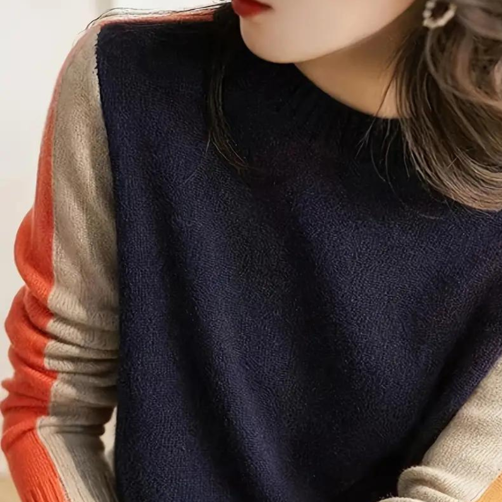 Donkerblauwe trui met lange mouwen, beige en rode strepen, gedragen door een vrouw. Modieuze dameskleding, herfst-winter stijl.