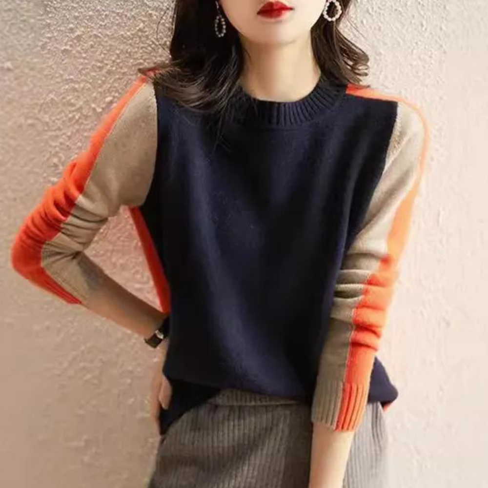 Vrouw draagt stijlvolle trui met kleurblokken in marineblauw, oranje en beige. Modieuze herfstkleding, trendy damesmode, casual chic outfit.