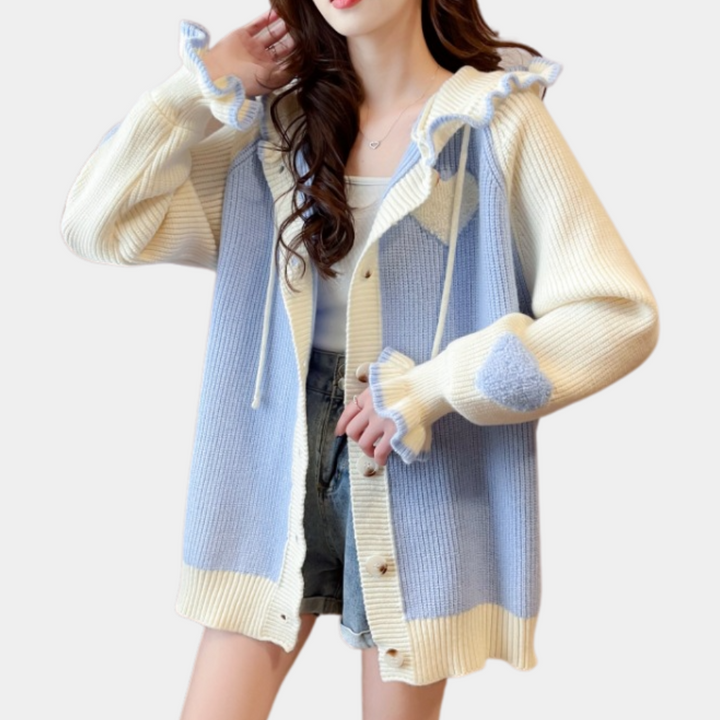 Vrouw draagt gebreid vest met blauwe en crèmekleurige strepen, ruches en knopen. Modieuze dameskleding, casual stijl, herfst/winter outfit.