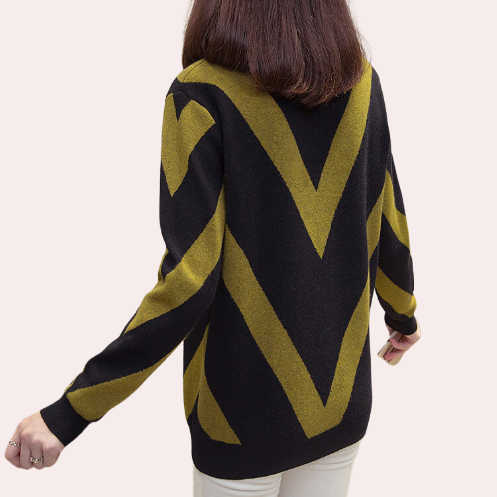 Vrouw in zwarte trui met grote gele V-patronen, rugaanzicht. Modieuze dameskleding, herfst/winter stijl, comfortabele casual outfit.