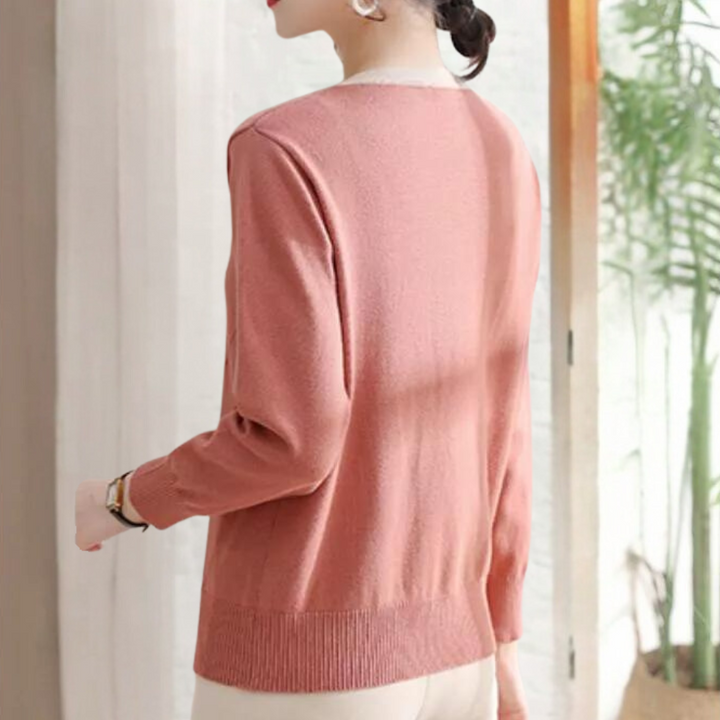 Vrouw in roze trui met lange mouwen, staand bij raam. Elegante damesmode, casual stijl, comfortabele kleding, herfstoutfit.