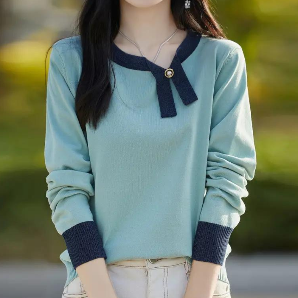 Vrouw in stijlvolle mintgroene trui met donkerblauwe accenten en knoopdetail, buiten gefotografeerd. Trendy damesmode, herfstkleding.