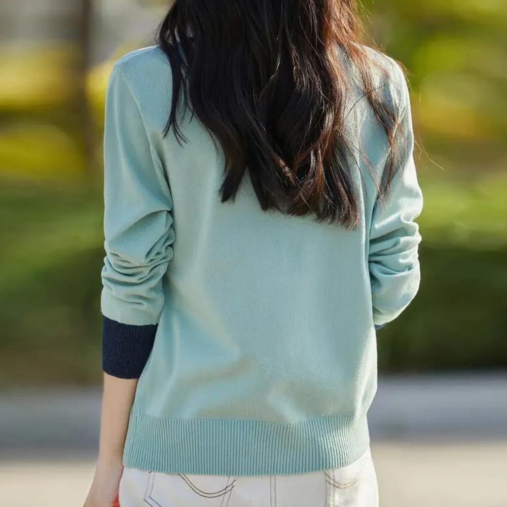 Vrouw in lichtblauwe trui met donkerblauwe mouwboorden, buiten gefotografeerd. Casual mode, herfstkleding, stijlvolle damestrui.