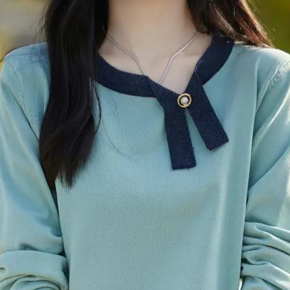 Vrouw in blauwe trui met zwarte kraag en gouden knoop, modieuze dameskleding, herfstmode, stijlvolle casual outfit, trendy damestrui.