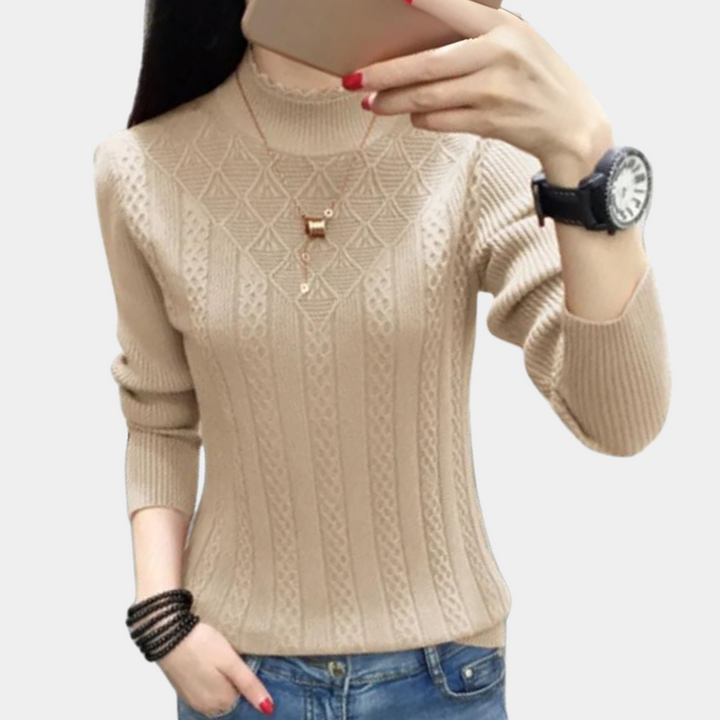 Beige gebreide damestrui met kabelpatroon, lange mouwen en hoge hals. Modieuze casual outfit, ideaal voor herfst en winter.