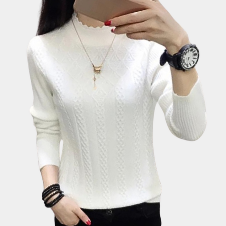 Witte damestrui met kabelpatroon, lange mouwen en ronde hals. Stijlvol voor herfstmode. Accessoires: horloge, ketting en armbanden.
