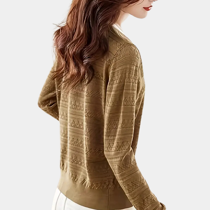 Vrouw draagt bruine gebreide trui met patroon, lange mouwen en ronde hals. Modieuze dameskleding, herfst-winter stijl, casual elegantie.