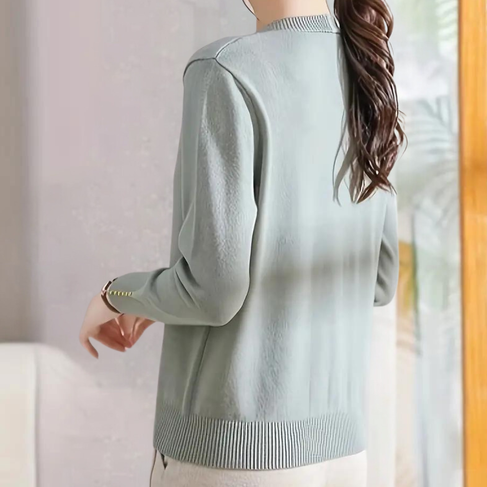 Vrouw in lichtblauwe trui met lange mouwen, knopen op de manchetten, casual stijl, modieuze dameskleding, comfortabele pasvorm, achteraanzicht.