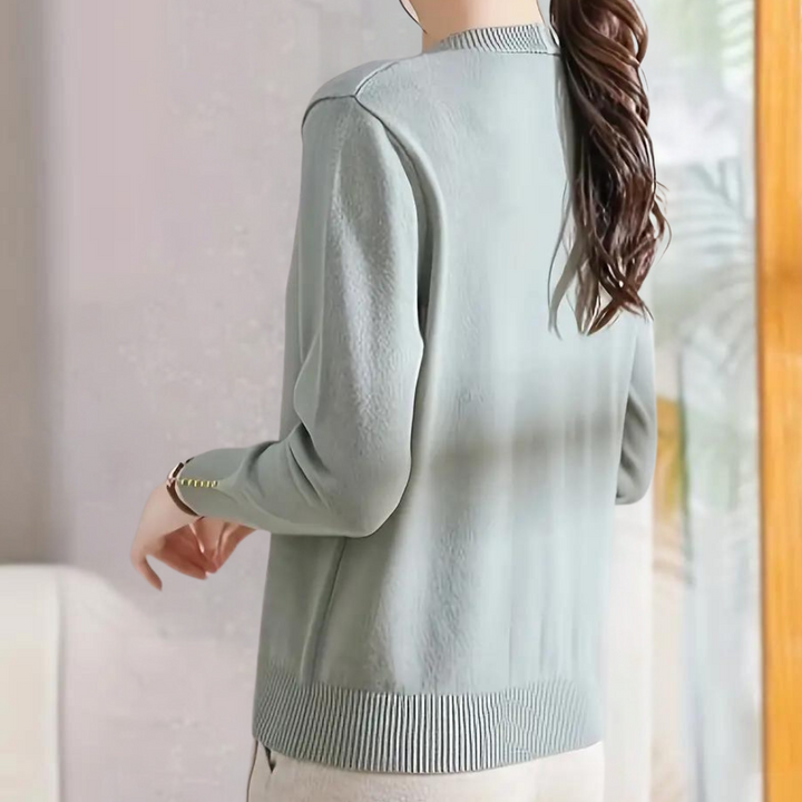 Vrouw in lichtblauwe trui met lange mouwen, knopen op de manchetten, casual stijl, modieuze dameskleding, comfortabele pasvorm, achteraanzicht.
