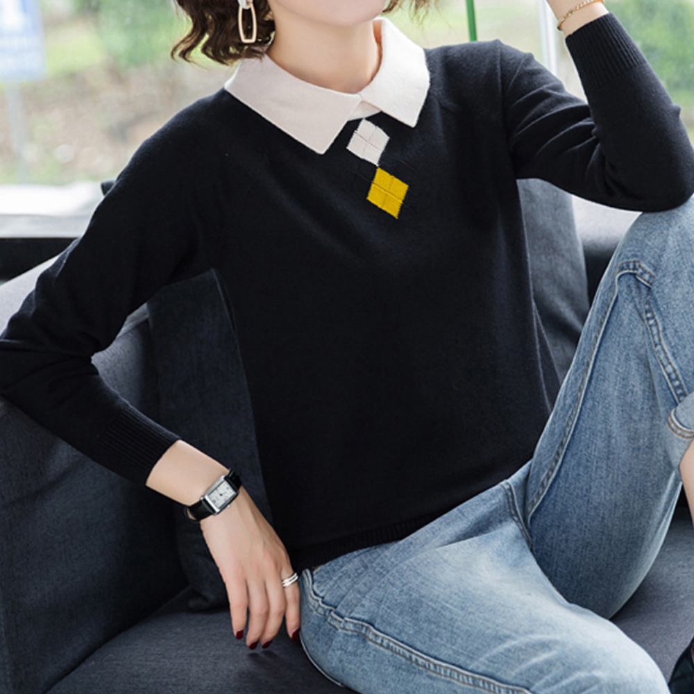 Vrouw in zwarte trui met witte kraag en geometrisch patroon, zittend op een bank. Modieuze dameskleding, casual outfit, herfstmode.