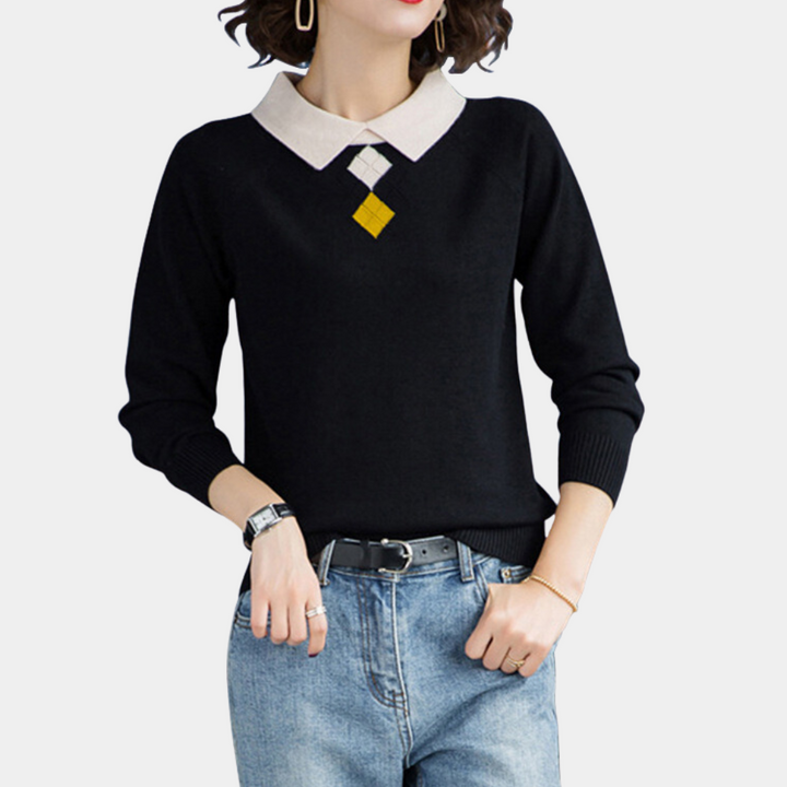Vrouw in zwarte trui met witte kraag en geometrisch patroon, draagt blauwe jeans. Modieuze dameskleding, casual outfit, herfstmode.