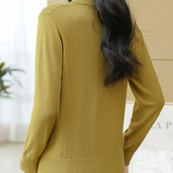 Achterkant van een vrouw in een mosterdgele trui, met lang donker haar, in een lichte kamer. Stijlvolle damesmode, herfstkleding, comfortabele trui.