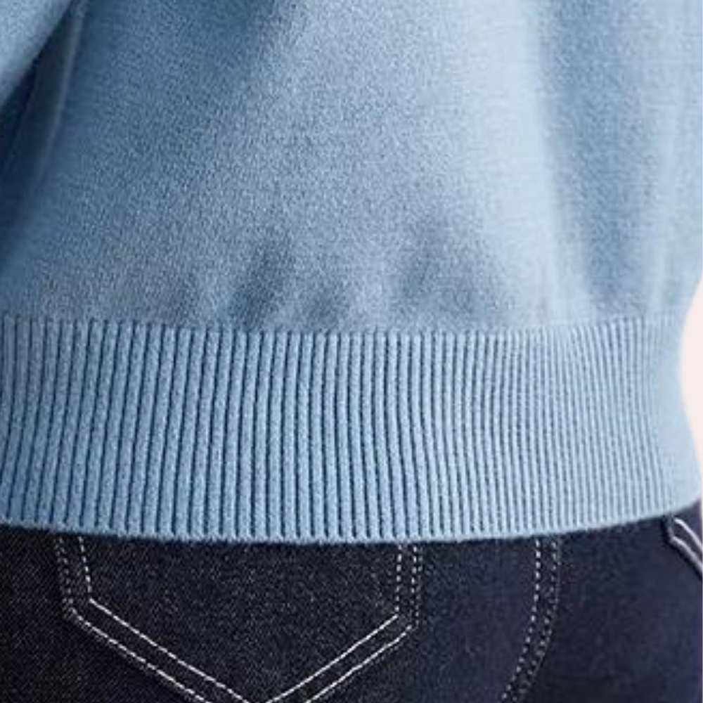 Lichtblauwe trui met geribde zoom, gedragen boven donkerblauwe jeans. Modieuze dameskleding, comfortabele casual outfit.