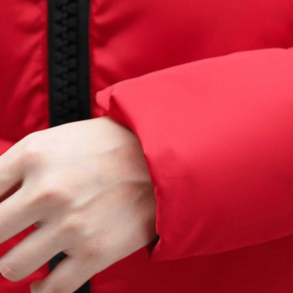 Rode winterjas met zwarte ritssluiting, close-up van mouw en hand. Hoogwaardige stof, warme kleding, modieuze winterjas voor koude seizoenen.
