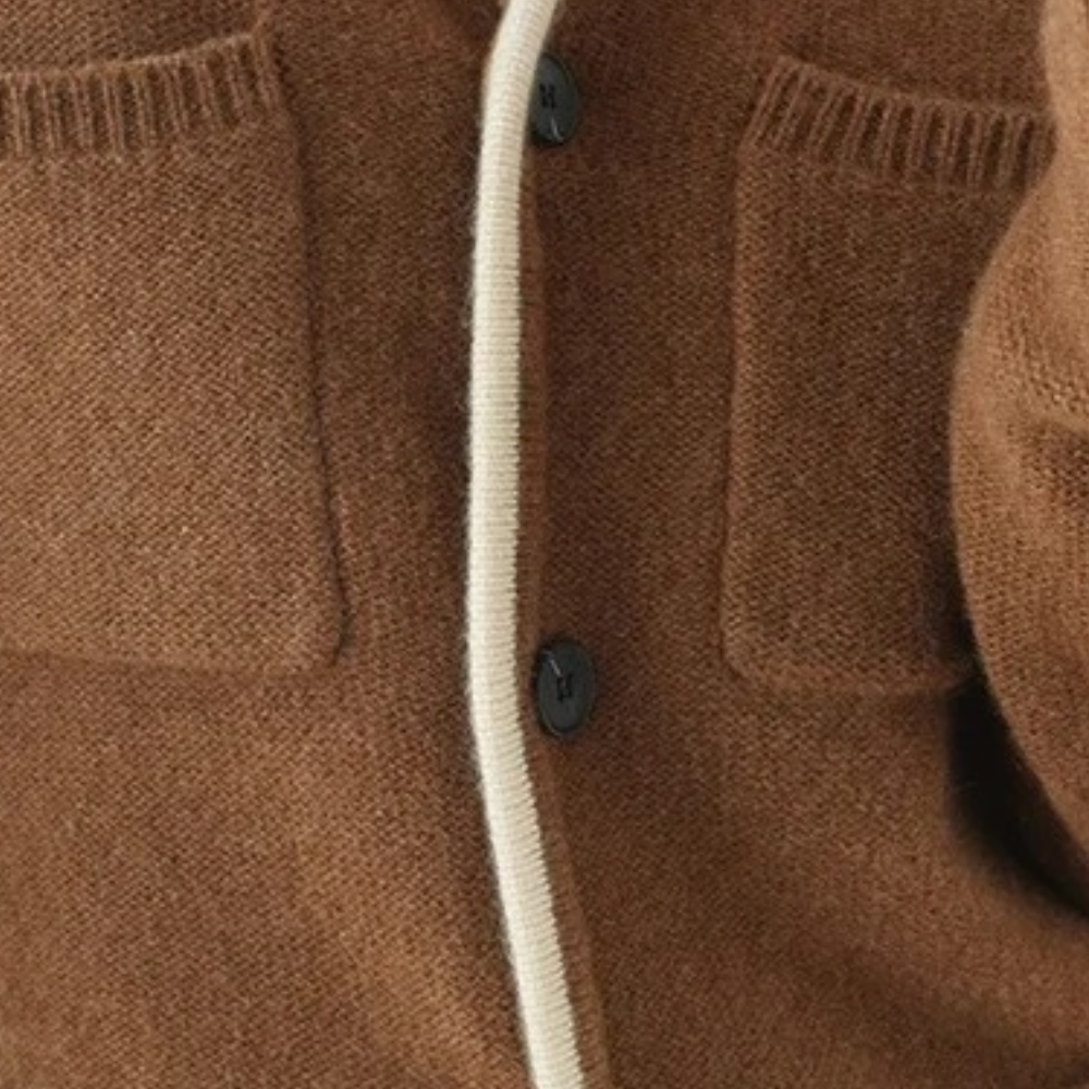 Bruine wollen cardigan met zwarte knopen en witte bies, close-up van zakken en textuur. Stijlvolle damesmode, herfstkleding, warme trui.