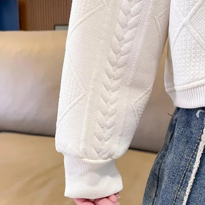 Witte gebreide trui met kabelpatroon, gedragen door persoon in blauwe jeans. Modieuze dameskleding, comfortabele winterstijl.