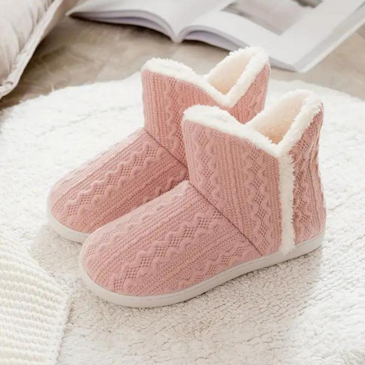 Roze gebreide pantoffels met witte voering op een zachte ondergrond, perfect voor wintercomfort en warmte. Ideaal voor thuisgebruik.