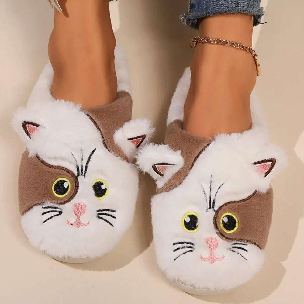 Pluche pantoffels met schattig kattengezicht ontwerp, bruine en witte kleuren, gedragen door persoon met enkelbandje. Perfect voor wintercomfort.