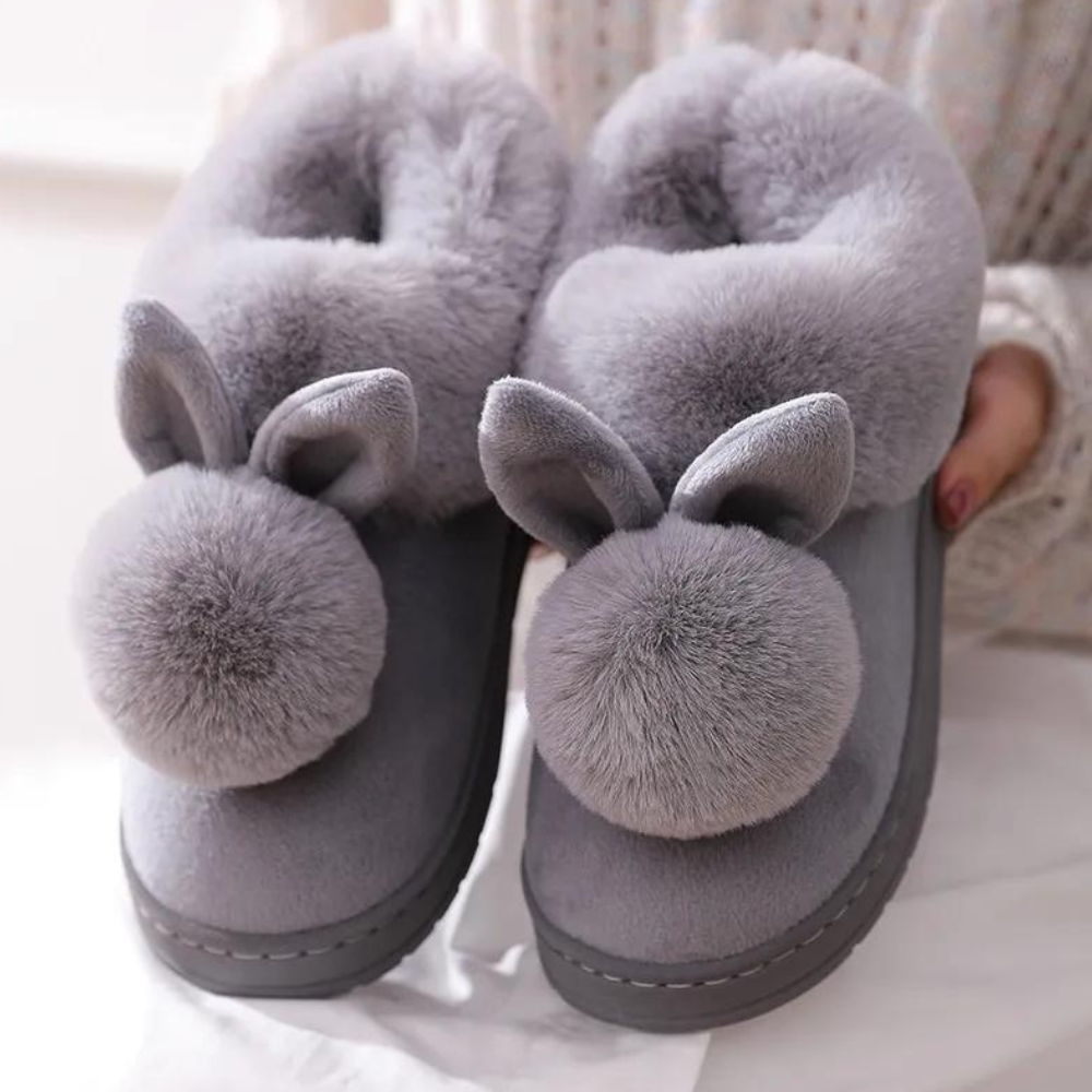 Grijze pluche pantoffels met konijnenoren en pompons, warme winterse huisschoenen voor dames, comfortabele en schattige sloffen voor binnenshuis.