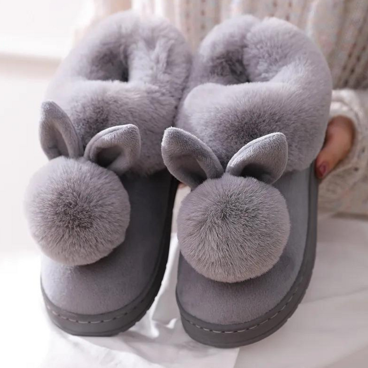 Grijze pluche pantoffels met konijnenoren en pompons, warme winterse huisschoenen voor dames, comfortabele en schattige sloffen voor binnenshuis.