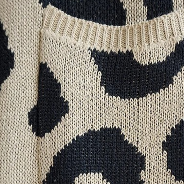 Beige en zwarte gebreide trui met abstracte patronen, close-up van textuur en details. Modieuze dameskleding, herfst-winter collectie.