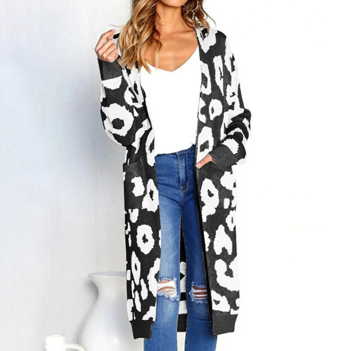 Vrouw draagt lange zwart-witte luipaardprint cardigan, witte top en gescheurde jeans. Modieuze dameskleding, casual stijl, herfstoutfit.