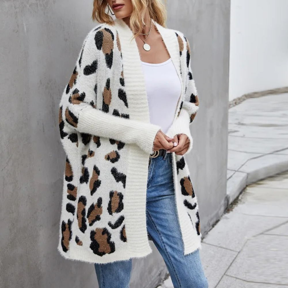 Vrouw draagt witte gebreide cardigan met luipaardprint, gecombineerd met blauwe jeans. Modieuze herfstoutfit, casual stijl, trendy dameskleding.