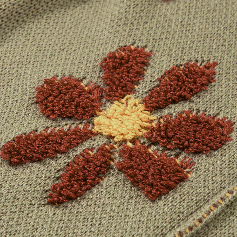 Geborduurde bloem op grijze stof, met rode en gele details. Perfect voor handwerk, textielkunst en DIY-projecten. Hoogwaardige borduurtechniek.