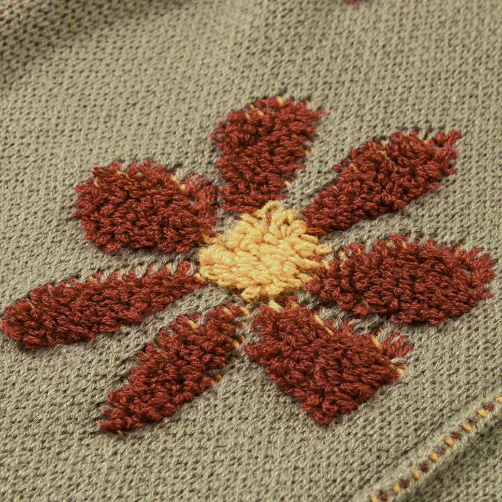 Geborduurde bloem op grijze stof, met rode en gele details. Perfect voor handwerk, textielkunst en DIY-projecten. Hoogwaardige borduurtechniek.