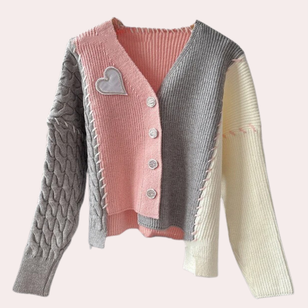 Roze en grijze gebreide damestrui met hartapplicatie, knopen en verschillende texturen. Modieuze en comfortabele kleding voor herfst en winter.
