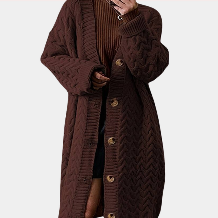 Vrouw draagt lange, bruine gebreide cardigan met knopen, over een geribbelde trui. Modieuze herfstkleding, comfortabele damesmode.