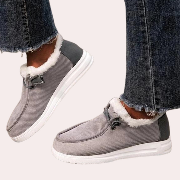 Grijze damesinstappers met bontvoering, comfortabele casual schoenen, witte zool, gedragen met gerafelde jeans. Perfect voor dagelijks gebruik.